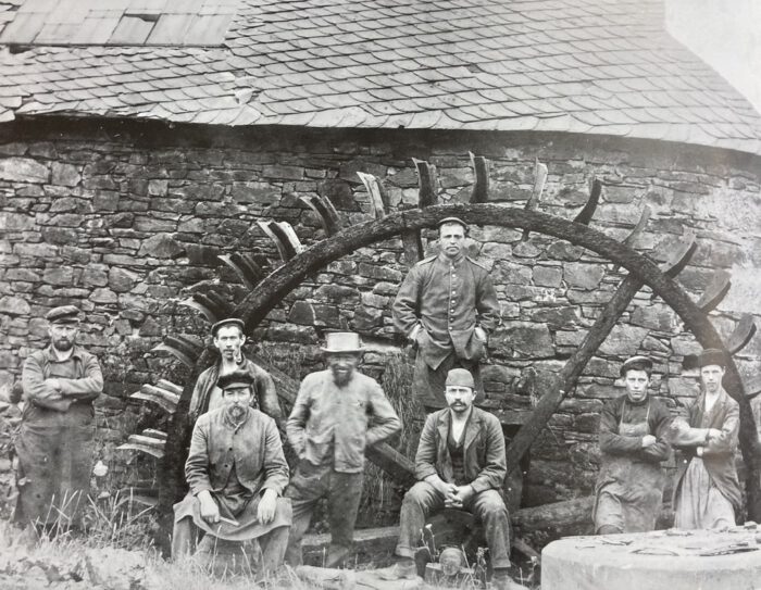 Schleifer vor dem Wasserrad einer Schleife am Idarbach